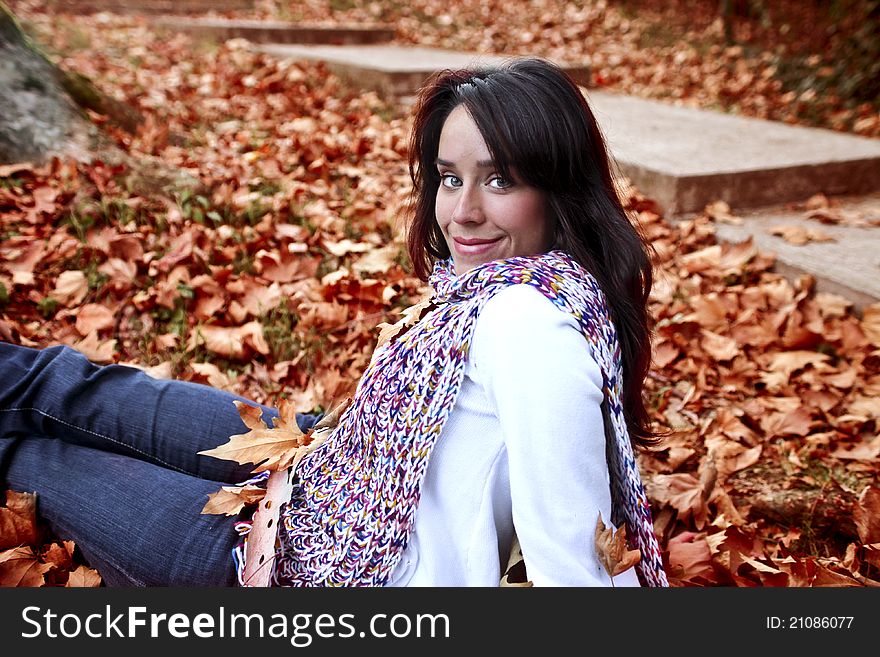 Beautiful smiling woman sitting in a park in autumn. Beautiful smiling woman sitting in a park in autumn