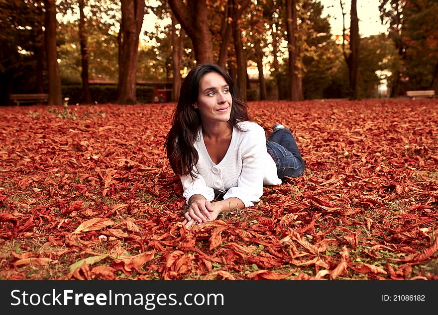 Beautiful smiling woman lying in a park in autumn. Beautiful smiling woman lying in a park in autumn