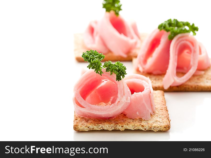 Photo of delicious crackers with ham and parsley on white background. Photo of delicious crackers with ham and parsley on white background