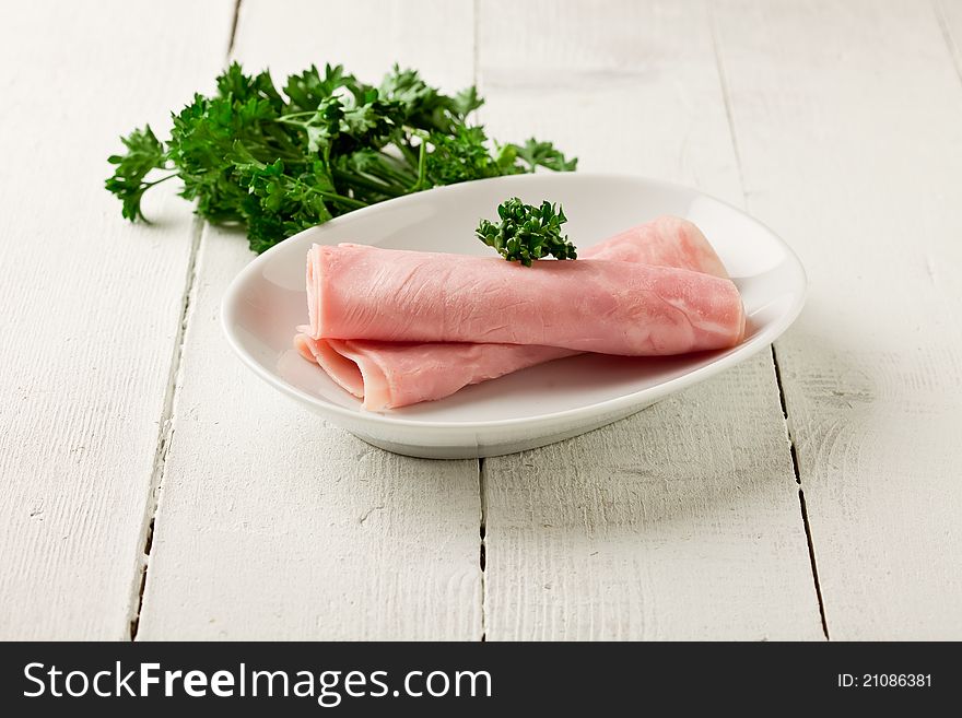Photo of delicious rolled ham with parsley on wooden table. Photo of delicious rolled ham with parsley on wooden table