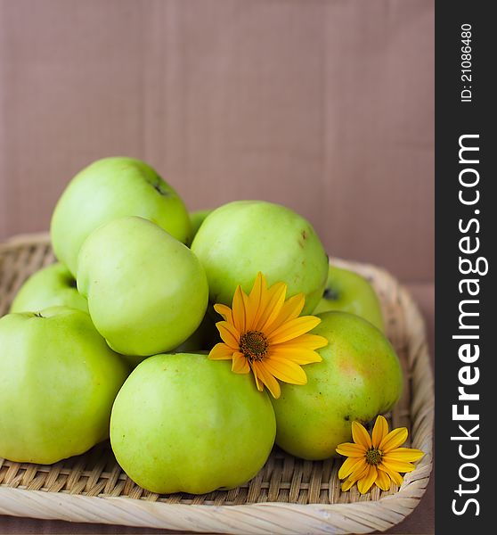 Green ecological apples, flowers and the brown background