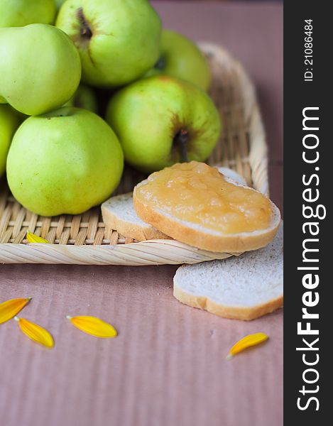 Green apple jam, bread, and the brown background with petals