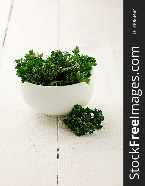 Delicious fresh parsley inside a white bowl on wooden table