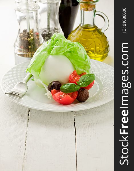 Delicious buffalo mozzarella with wrapped lettuce and tomatoes on wooden table