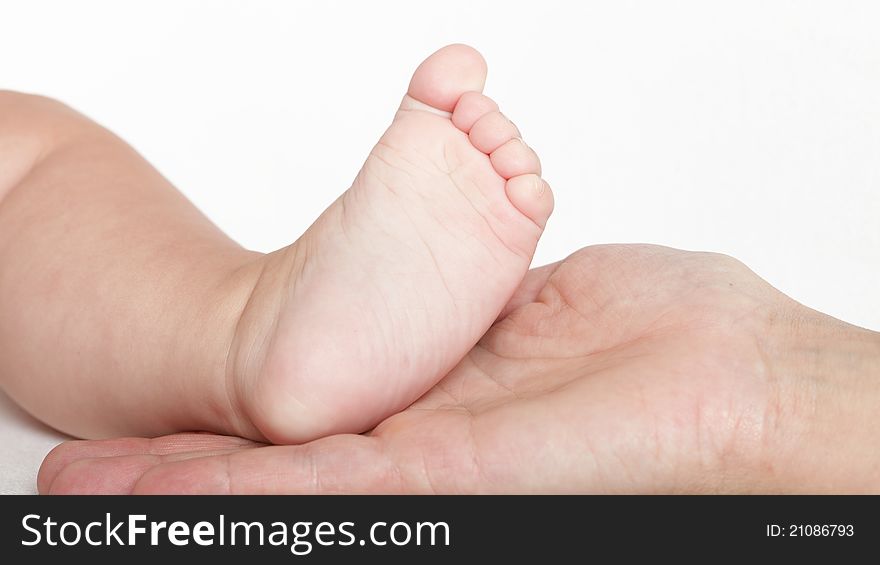 Baby foot in mother hands on white background