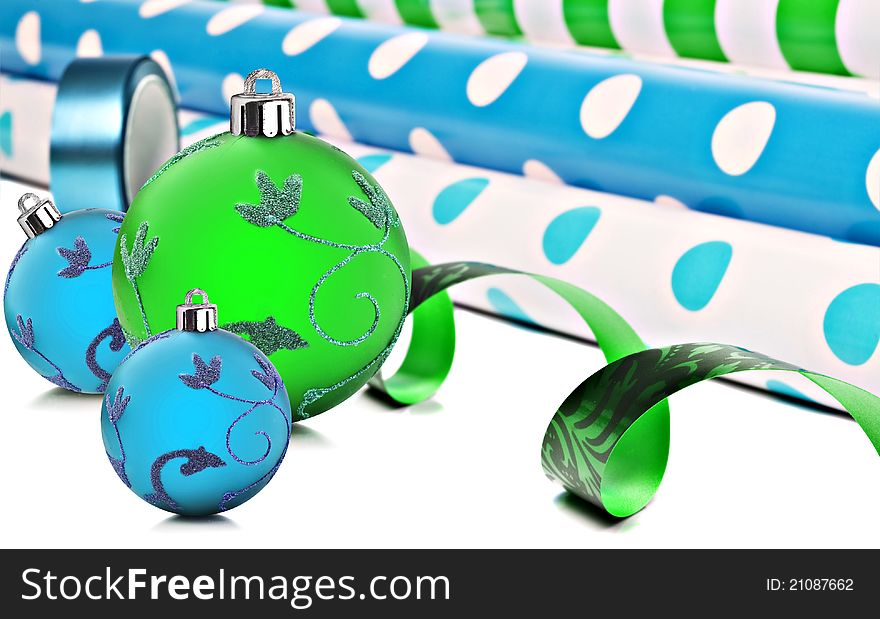 Rolls of gift wrapping paper and ribbon with blue and green christmas baubles. Rolls of gift wrapping paper and ribbon with blue and green christmas baubles