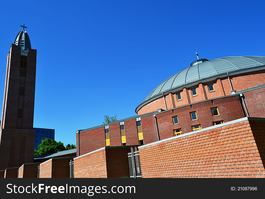 Perspective view of a modern church building with its belfry, cupola, windows and fencing.