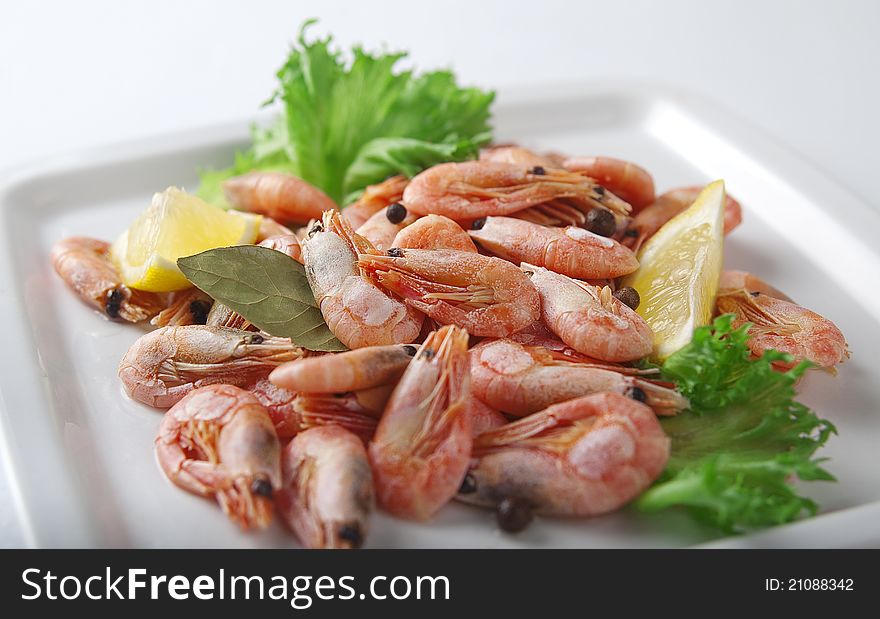 Coldwater shrimps with lettuce and lemon on the black plate