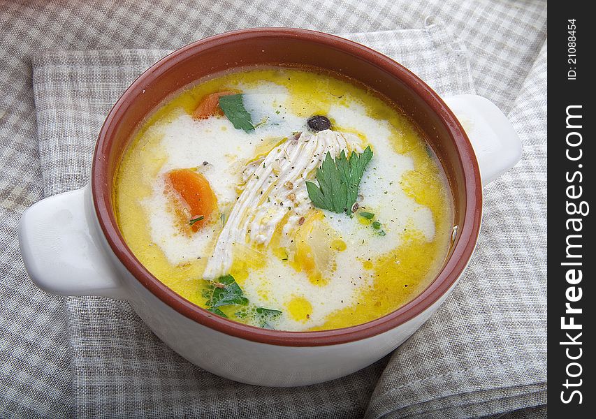 Bowl with chicken soup on the tablecloth