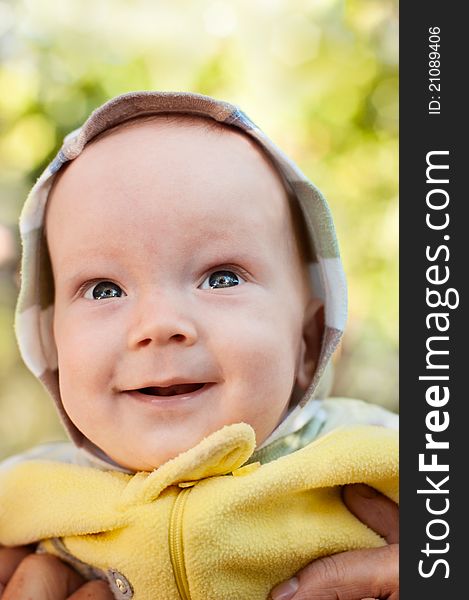 Happy baby boy on mother hands looking up