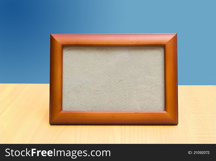 Frame on a wooden table and a blue backdrop