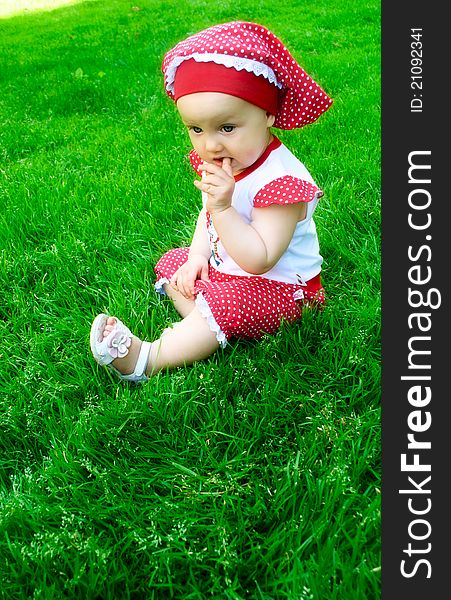 A cute baby girl is sitting on the grass on summer day. A cute baby girl is sitting on the grass on summer day