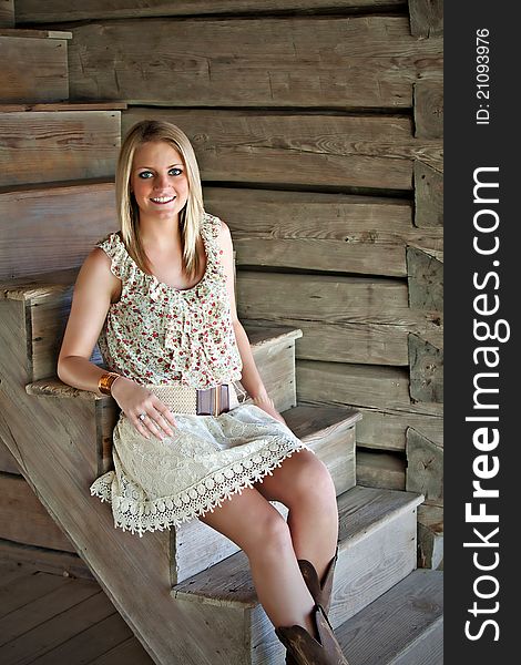 Portrait of beautiful smiling teenage girl sitting next to a log wall. Portrait of beautiful smiling teenage girl sitting next to a log wall.