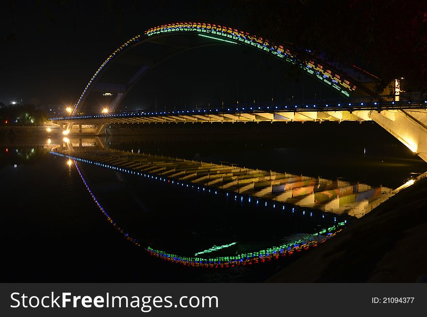 Illuminated bridge in the night reflected in still river. Illuminated bridge in the night reflected in still river