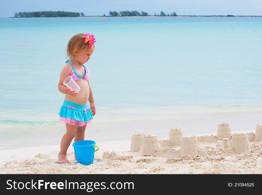 A cute baby girl is building a sand castle on the beach. A cute baby girl is building a sand castle on the beach