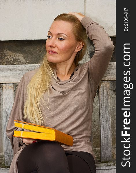 Woman sitting on a bench holding a book.