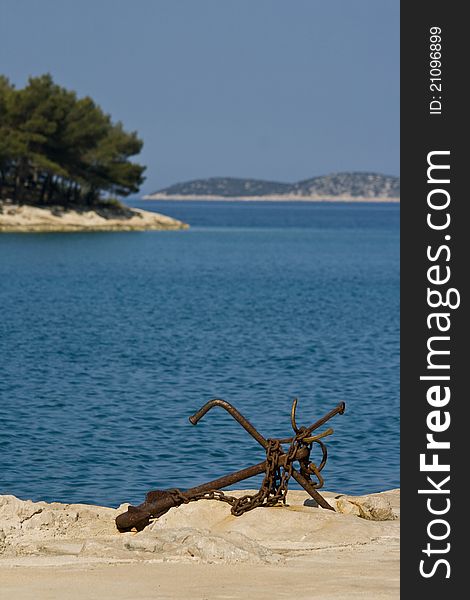 Old rusty anchor on the rocky coast of Tribunj. Old rusty anchor on the rocky coast of Tribunj