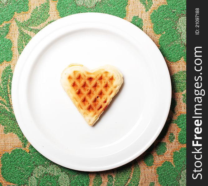 Sweet wafer heart on dish, on retro background