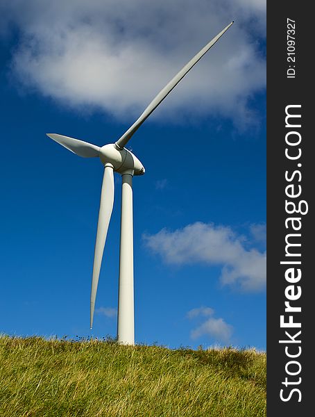 White windmill on a green grass and blue sky background