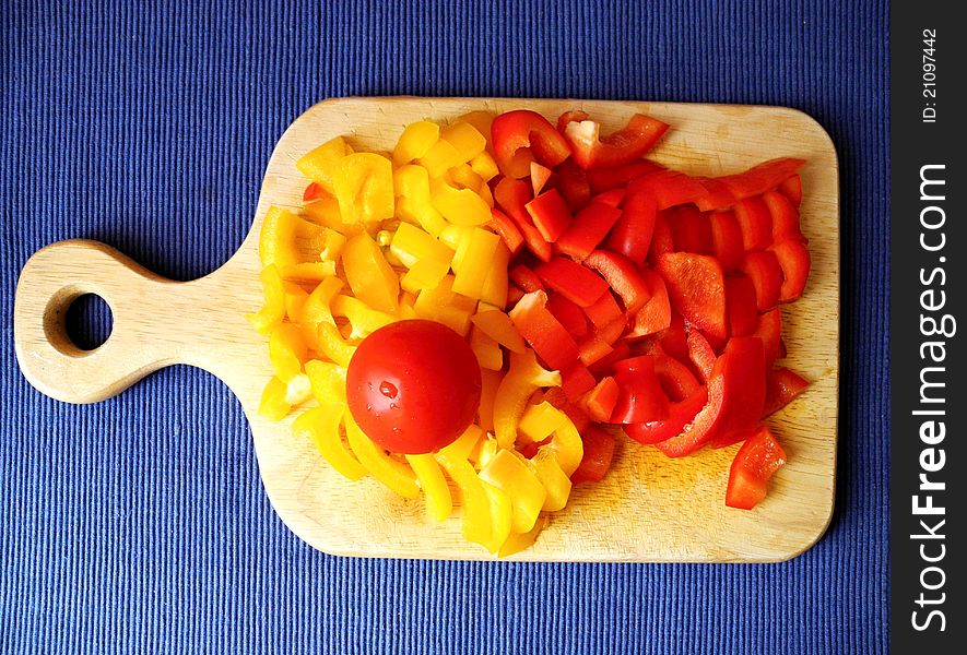 Sliced tomato and peppers on a wooden chopping board. Sliced tomato and peppers on a wooden chopping board.