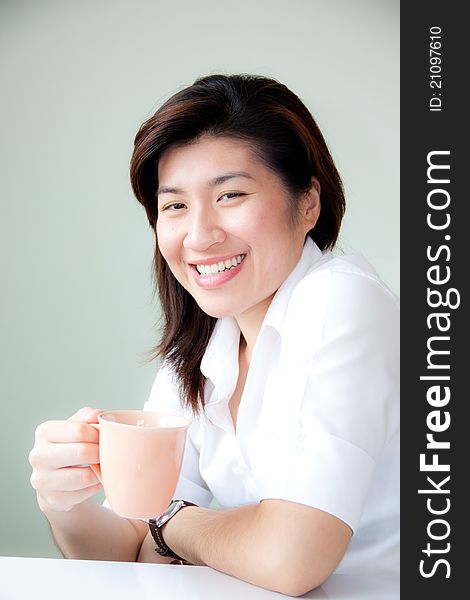 Smiling young asian woman holding a cup