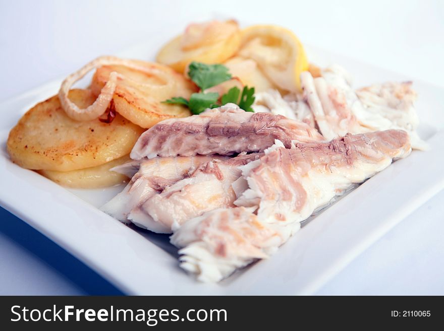 Gilthead Bream fish cooked with potato slices in a white dish