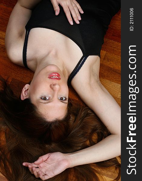 A woman, lying on her back on a wooden floor. A woman, lying on her back on a wooden floor