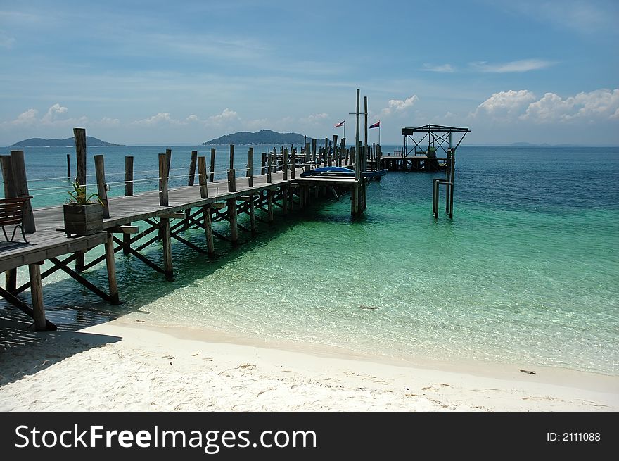 Old wooden jetty with clear water and blue sky