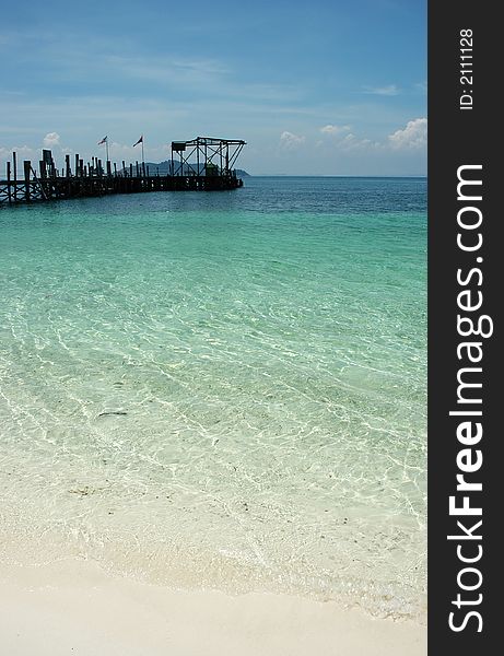 Old wooden jetty with clear water and blue sky