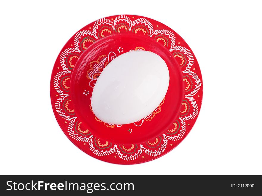 One white egg on a painted red plate. One white egg on a painted red plate.