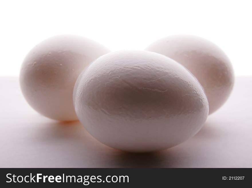 Three white eggs on the grey background. Three white eggs on the grey background.