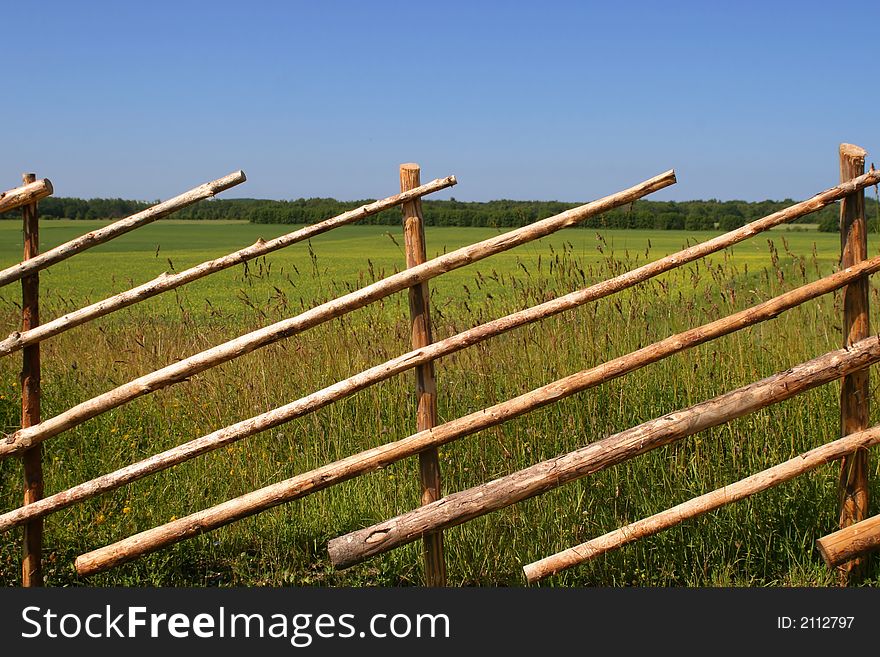 Old wooden fence near big yellow field