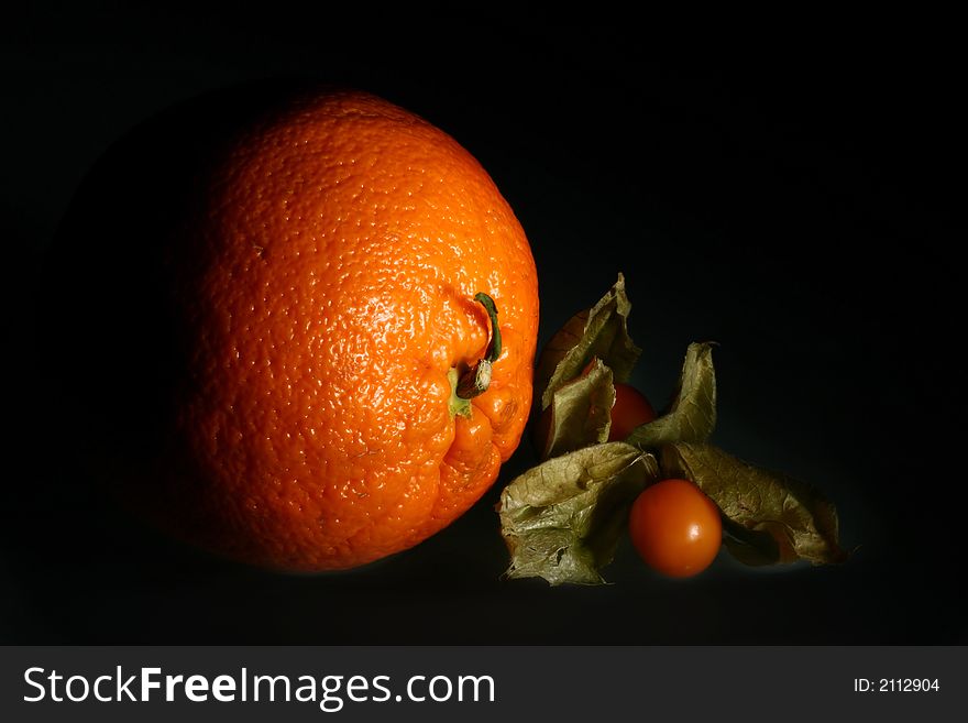 Small ripe goldenberry and big ripe orange. Small ripe goldenberry and big ripe orange