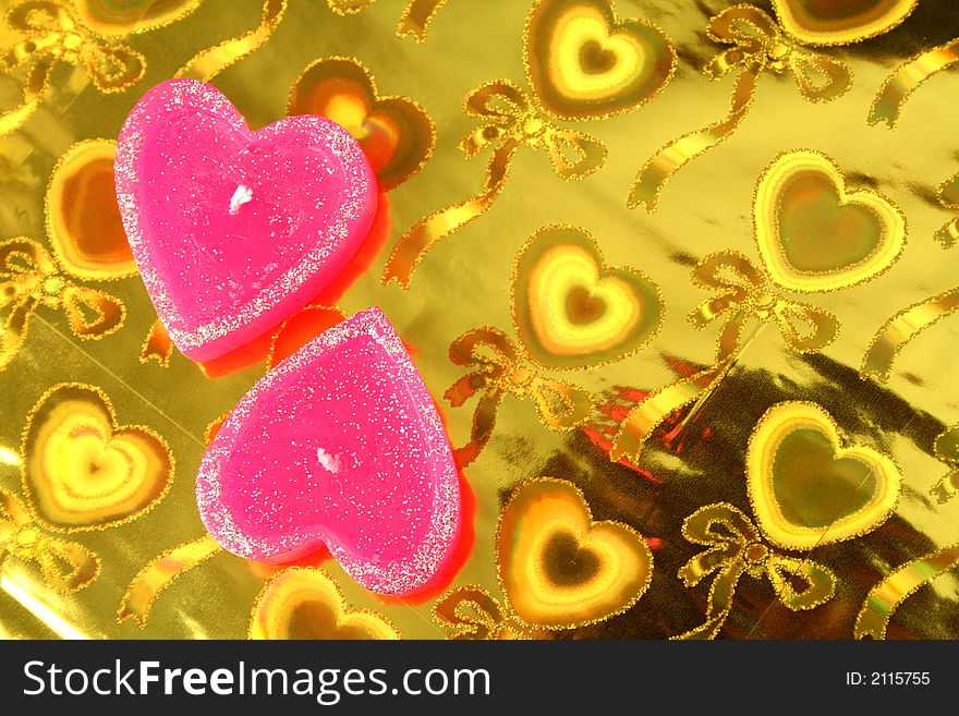 Two candles in the form of hearts on a celebratory background