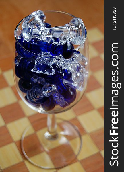 Wine glass with chess pieces inside stending on the chessboard. Wine glass with chess pieces inside stending on the chessboard