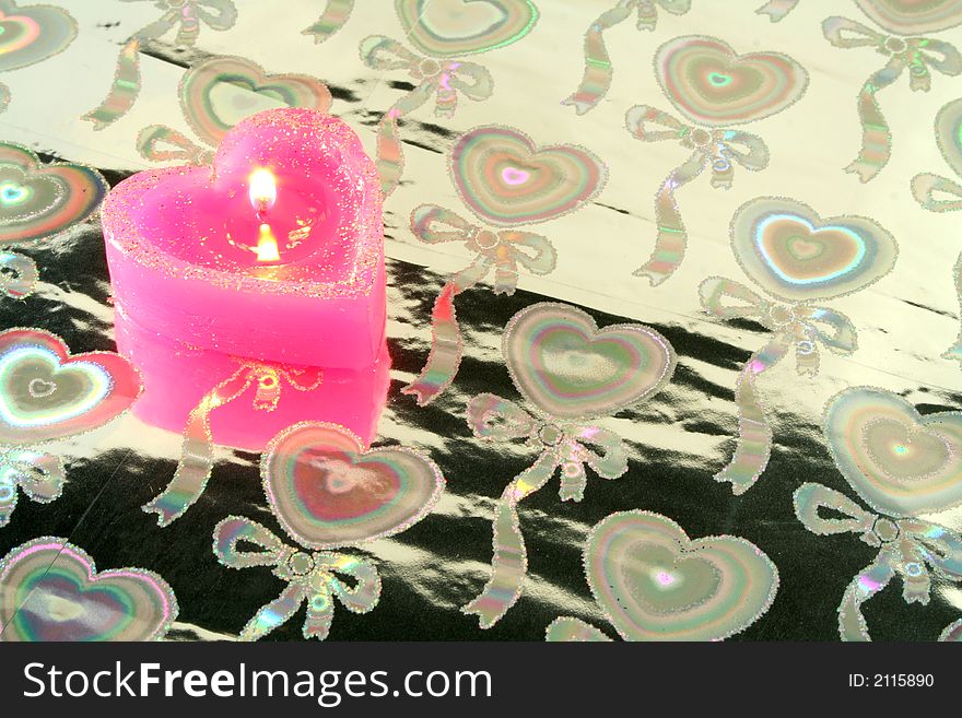 Candle in the form of heart on a silvery background