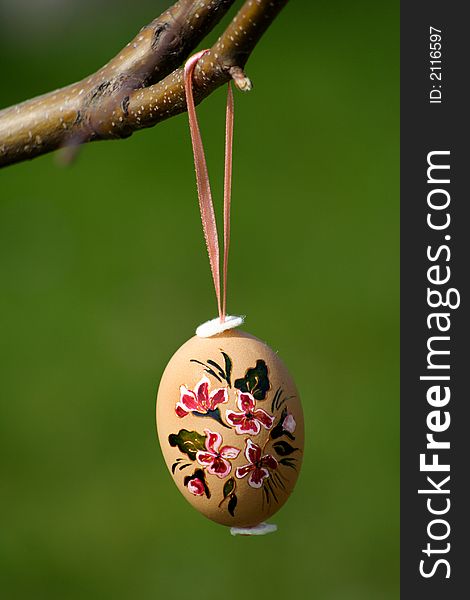 Handpainted easter egg hanging from a barnch