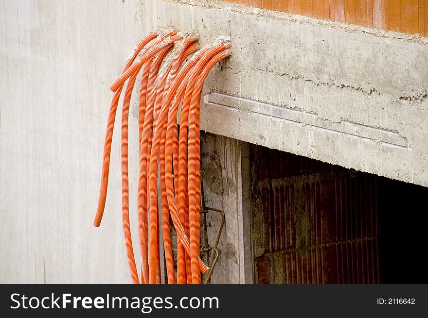 Orange pipes coming out of a raw concrete wall. Orange pipes coming out of a raw concrete wall.