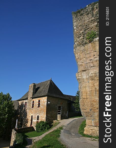 Large natural stone wall overlooking a village house in Turenne, correze, france