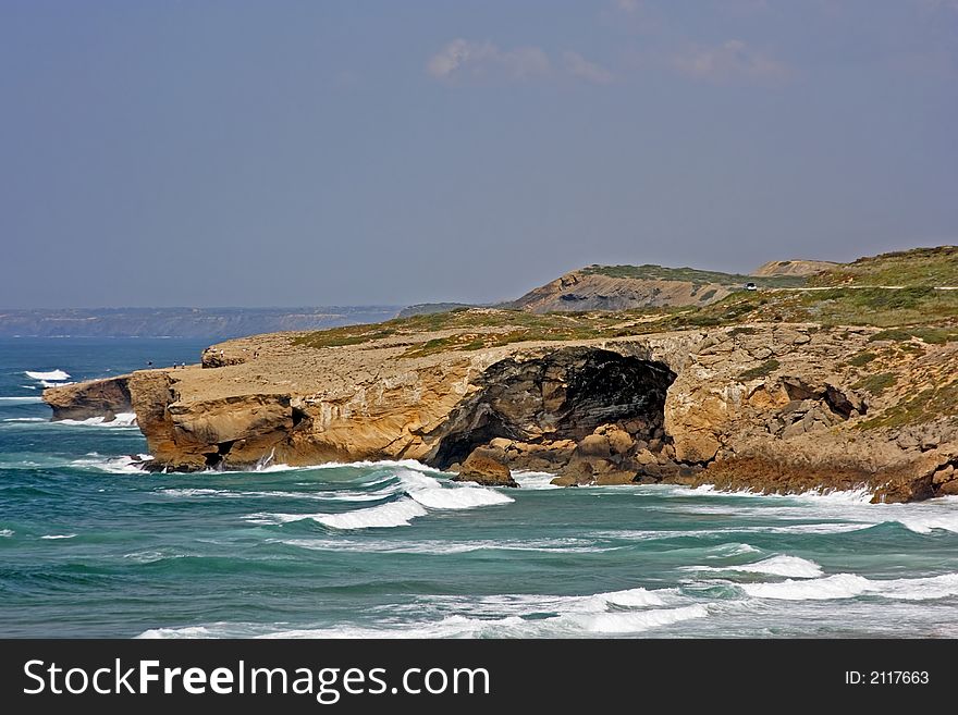 Rock at the coast in Portugal with the atlantic ocean and a blue sky