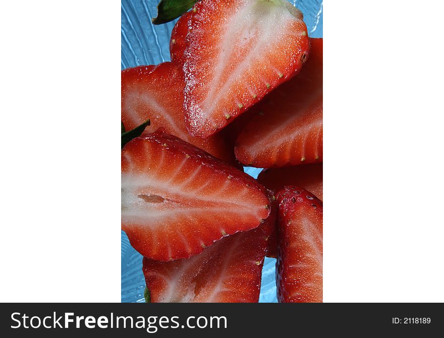 Strawberries cut in half on a clear glass plate. Strawberries cut in half on a clear glass plate