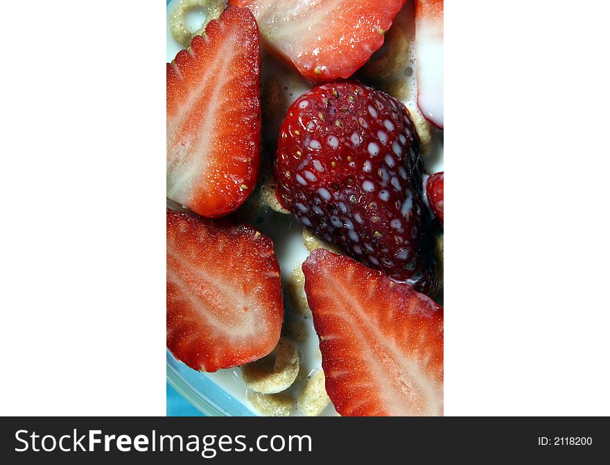 Strawberries in bowl of cereal with milk close-up on blue background. Strawberries in bowl of cereal with milk close-up on blue background