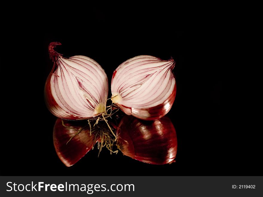 Two halve cutted onions on mirror with black background