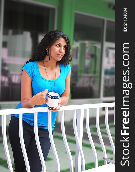 Beautiful woman drinking coffee in the morning on a colorful balcony