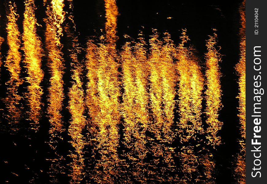 An abstract image of fiery looking lights reflected on a flowing river. An abstract image of fiery looking lights reflected on a flowing river.