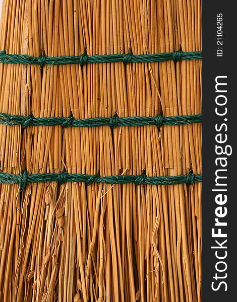 A closeup vertical image of tan boom straw with green stitching. A closeup vertical image of tan boom straw with green stitching.