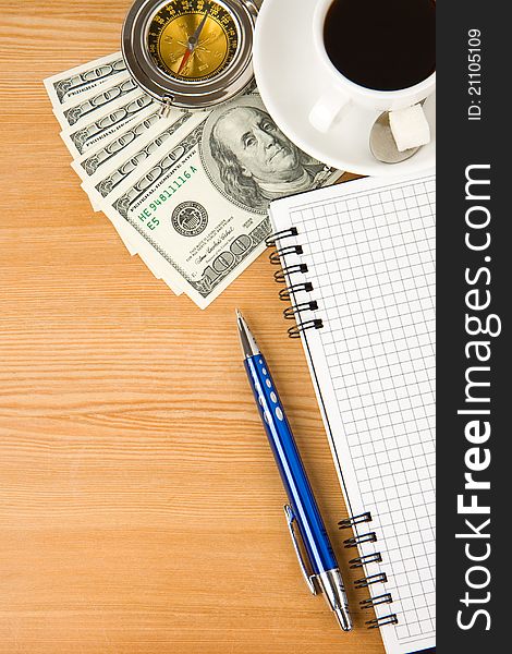 Notebook and coffee with dollar on wood table