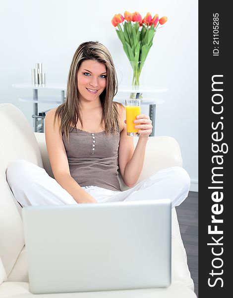 Woman on sofa with laptop and orange juice