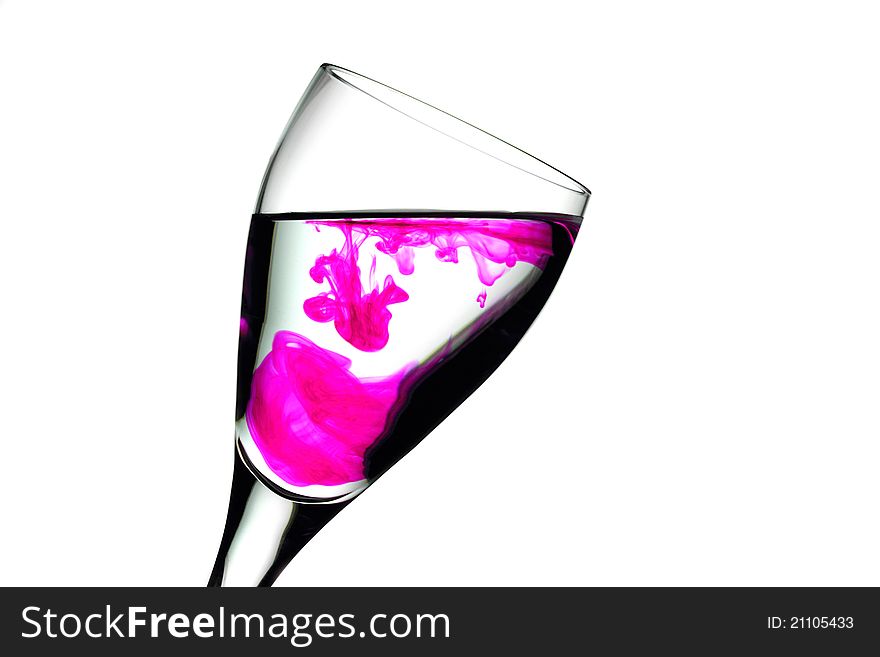 Wine glass with a splash of food colouring set against a white background. Wine glass with a splash of food colouring set against a white background