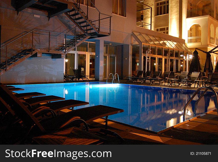 Swimming pool in the evening, with beautiful lights, and chairs nearby. Swimming pool in the evening, with beautiful lights, and chairs nearby